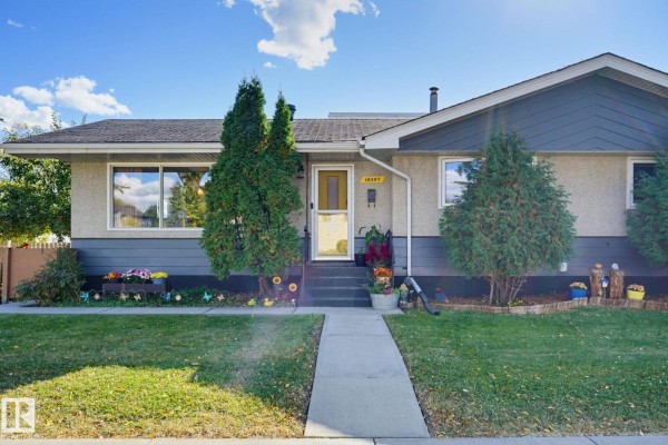 Entrance to one side of the duplex with a yellow door, windows, and walkway. - 10207 & 10209 120 Av Nw, Edmonton