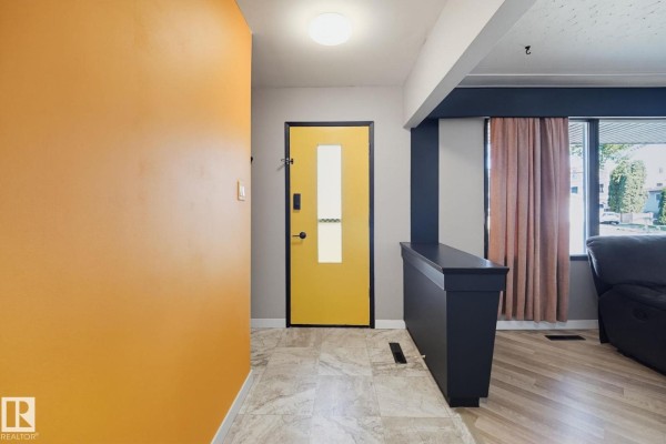 Interior entryway with orange and grey walls, a yellow door, tile flooring, and dark blue accents. - 10207 & 10209 120 Av Nw, Edmonton