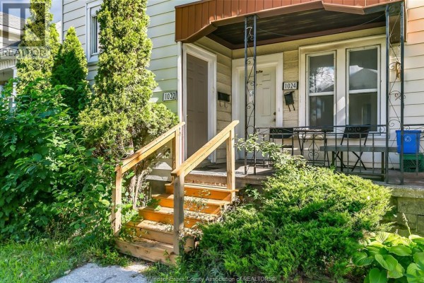Close-up of the duplex entrance with wooden stairs, a small covered porch with a table and chairs. - 1022-1024 Lincoln Rd, Windsor