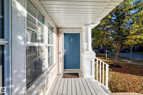Close-up of the front door, a blue-painted door with white trim, columns, and a white railing. - 1022 80 St Sw, Edmonton