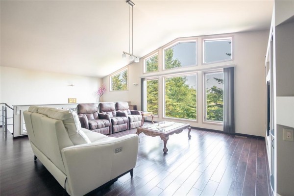 Spacious living room with white and brown sofas, recliners, and dark hardwood floors. - 1022 Liss Road, St Andrews