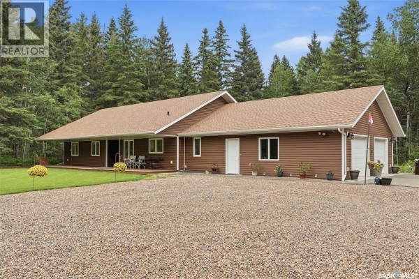 Exterior side view of a brown bungalow with a gravel driveway and a three-car garage. - 1022 Rooster Road, Turtle Lake