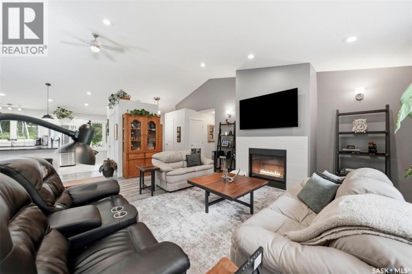 Living room with a fireplace, large television, sectional sofa, and view of the kitchen area. - 1022 Rooster Road, Turtle Lake