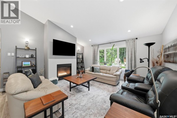 Living room with a fireplace, television, sofas, and a view of the backyard through the curtains. - 1022 Rooster Road, Turtle Lake