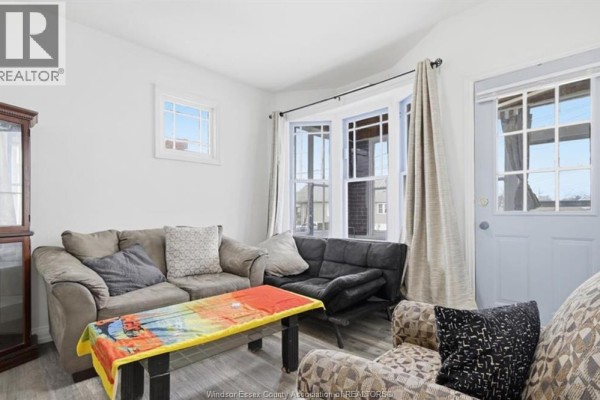 Dining area with a round table, a wooden hutch, and an archway leading to a living room. - 1023 Hall Avenue, Windsor