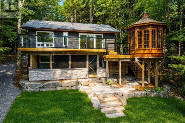 Exterior view of a wooden cottage with a stone foundation, deck, and hexagonal gazebo. - 1023 Strachan Point Road, Muskoka Lakes)