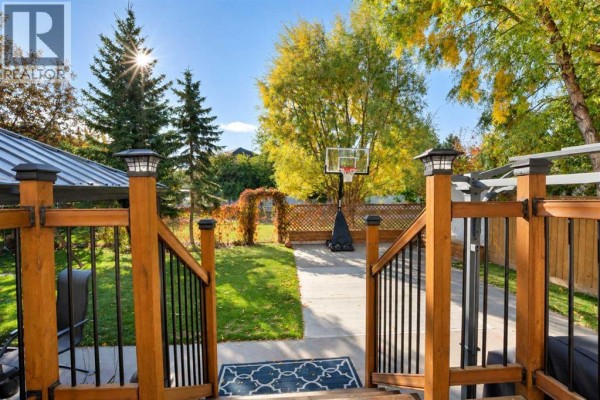 View from the deck stairs looking out to the backyard, featuring a basketball hoop and mature trees. - 10235 75a Avenue, Grande Prairie