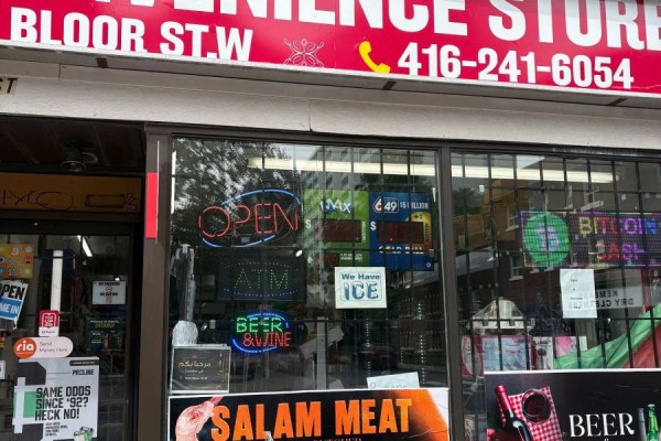 Close-up view of the store windows, showing 'OPEN' and 'ATM' neon signs, and various advertisements. - 1024 Bloor Street W, Toronto