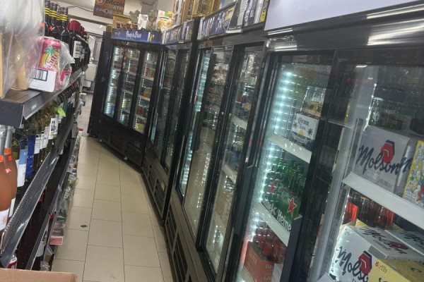 Interior view of the store showing multiple rows of glass-doored refrigerators stocked with drinks. - 1024 Bloor Street W, Toronto