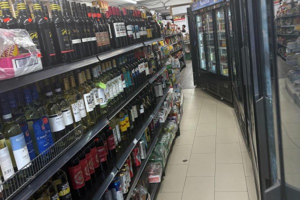 Interior view of the store displaying shelves stocked with wine bottles and drinks, adjacent to refrigerators. - 1024 Bloor Street W, Toronto