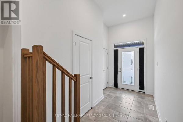 Interior entryway with tile floor, white walls, and a wooden staircase railing. - 1024 Montelena Road, Ottawa