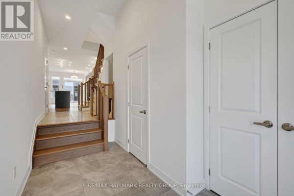 Hallway interior view with stairs, doors, and view into living area. - 1024 Montelena Road, Ottawa