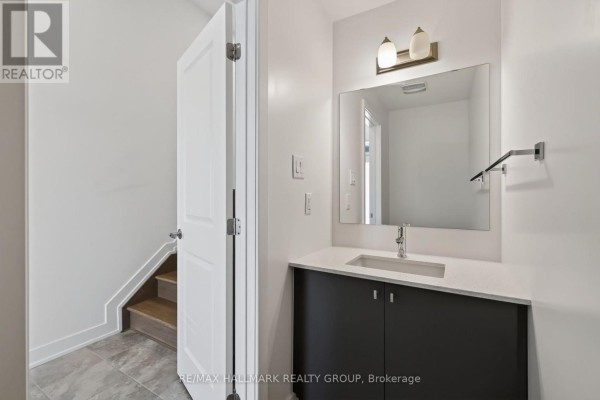 Powder room with vanity, sink, mirror, and towel rack, next to stairs. - 1024 Montelena Road, Ottawa
