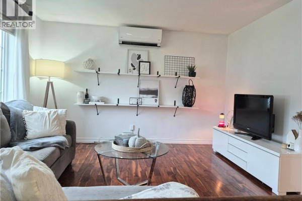 Living room with large sectional sofa, round glass coffee table, and wood floor. - 1024 Rue Misho, Beresford