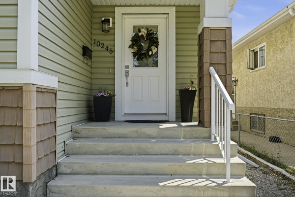 Close-up of the front door entrance with steps, railings, and potted plants. - 10245 152 St Nw, Edmonton