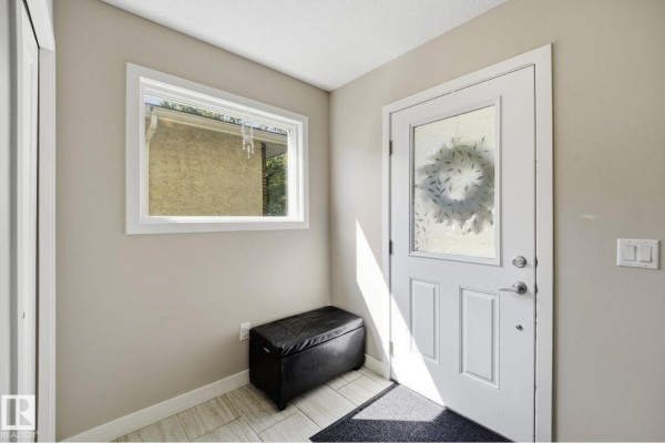 Interior foyer with a white door, a small window, and a black storage bench. - 10245 152 St Nw, Edmonton