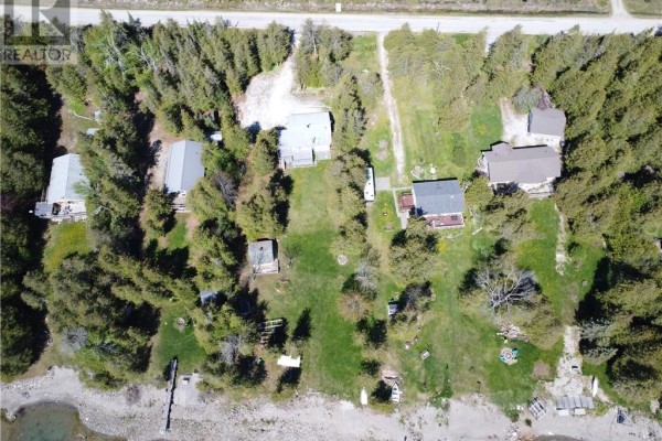Aerial view of property with multiple small buildings surrounded by trees and waterfront. - 1028 Bay Estates, Nemi