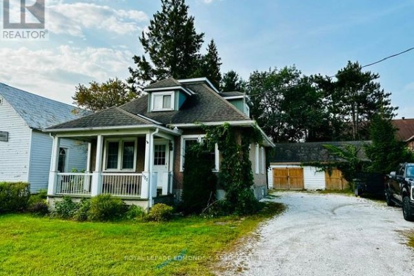 Side view of the house with gravel driveway and surrounding trees. - 1028 Pembroke Street E, Pembroke