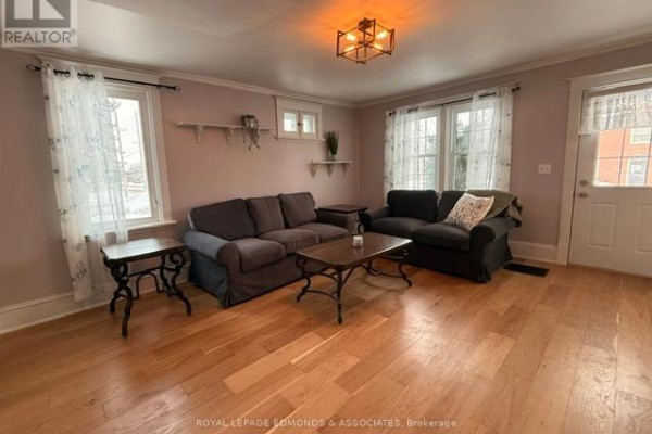Living room with two sofas, hardwood flooring, and large windows. - 1028 Pembroke Street E, Pembroke