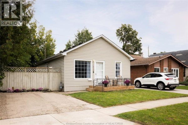 Exterior front view of a beige vinyl-sided bungalow with a driveway and a white SUV. - 1028 Reedmere Rd, Windsor