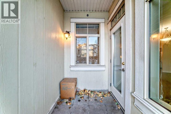 Open living area with hardwood floors, light walls, and access to the kitchen. - 103, 10 Auburn Bay Link Se, Calgary