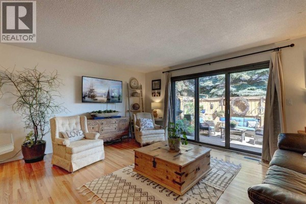 Interior view of a townhouse foyer with a dark grey front door and hanging light fixture. - 103, 1305 Glenmore Trail Sw, Calgary