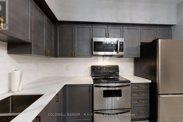 Kitchen with dark grey cabinets, white subway tile backsplash, and stainless steel appliances. - 103 - 157 Wellington Street E, New Tecumseth