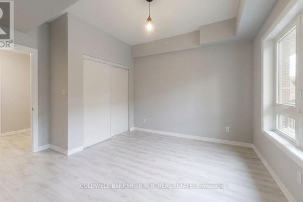 Bedroom with light grey walls, large closet, light wood flooring, and a window. - 103 - 157 Wellington Street E, New Tecumseth