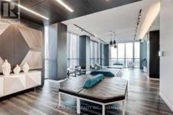 A modern apartment building lounge area with minimalist furniture and large windows. - 103 - 20 Thomas Riley Road, Toronto