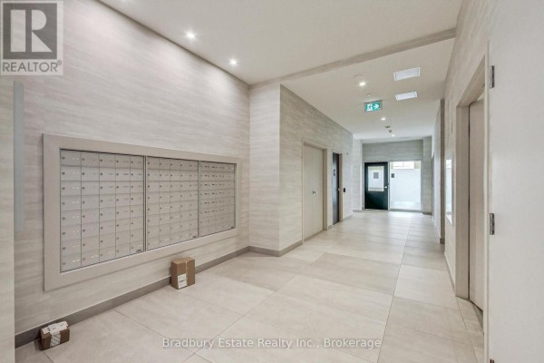 Apartment building hallway with a wall of mailboxes, tiled floors, and elevators. - 103 - 2750 King Street E, Hamilton