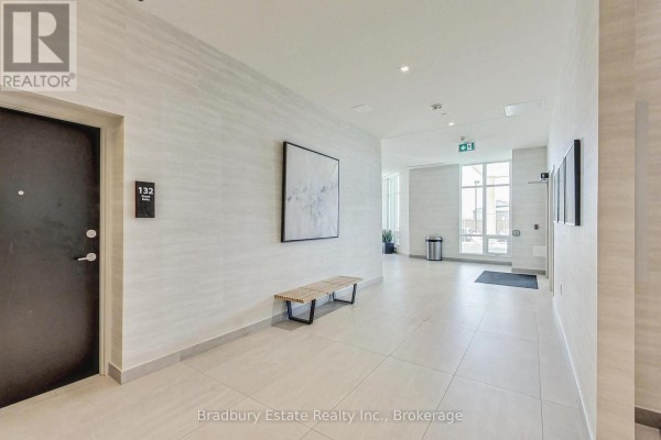 Apartment building hallway with a suite door labeled 132, a wooden bench, and tiled floors. - 103 - 2750 King Street E, Hamilton