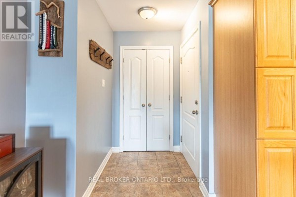 Hallway entrance with blue walls, tile floor, double closet doors, and wooden cabinets. - 103 - 32 La Croisee Street, Russell