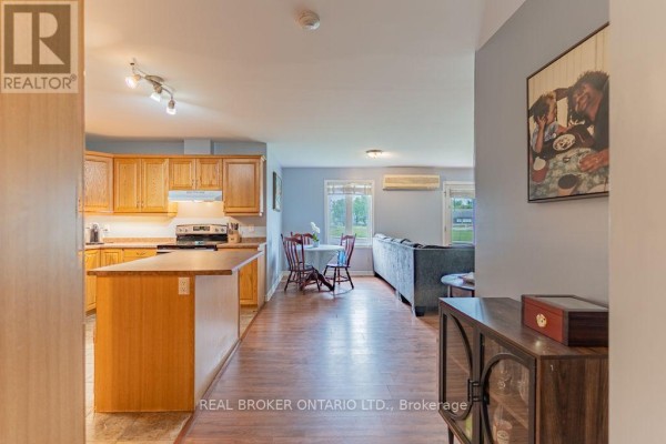 View from kitchen island showing dining area with table and living room with sofa. - 103 - 32 La Croisee Street, Russell