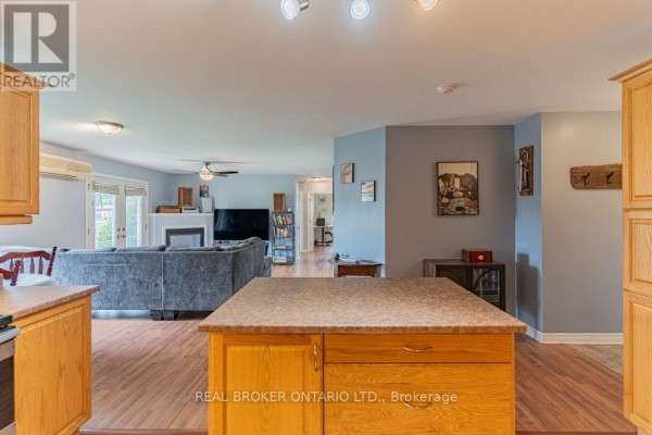 View from kitchen island showing living room with fireplace, sofa, and doorway to hallway. - 103 - 32 La Croisee Street, Russell