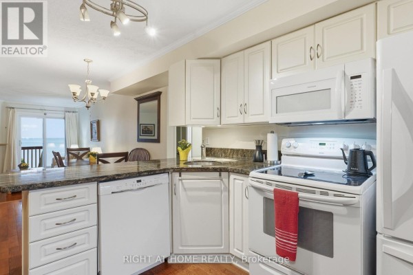 Kitchen with white cabinets, granite countertops, and white appliances adjacent to dining area. - 103 - 43 Olive Crescent E, Orillia