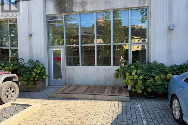 Exterior view of the building with large windows, greenery, and parking spaces. - 103 - 510 King Street E, Toronto