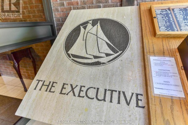 Close-up of building name plaque reading "THE EXECUTIVE" with a graphic of a sailboat. - 103 - 55 Water Street E, Brockville