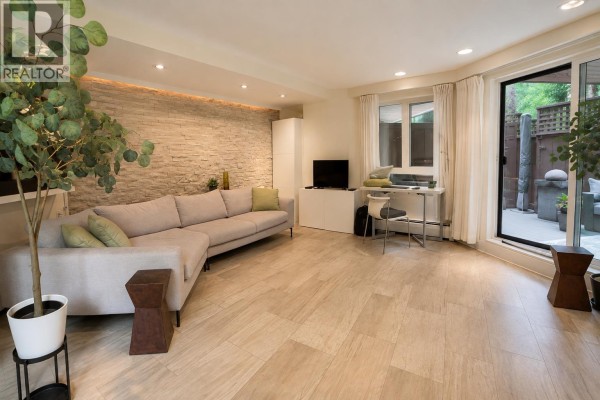 Spacious living area with sectional sofa, desk, and sliding glass door. - 103 1855 Nelson Street, Vancouver