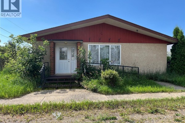 Front entrance of a commercial building with a ramp, steps, and overgrown greenery. - 103 1st Avenue W, Paynton