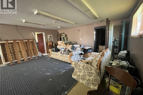 Interior room with two floral sofas, office equipment, and overhead fluorescent lighting. - 103 1st Avenue W, Paynton