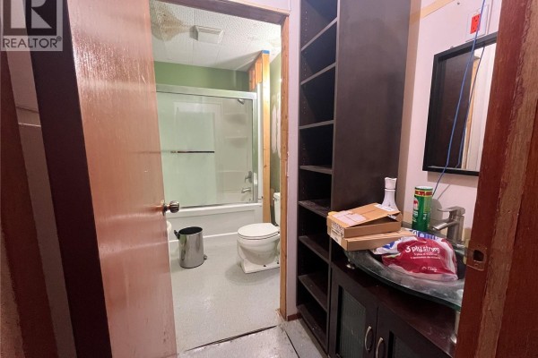 View into a bathroom with a bathtub, toilet, and a vanity with shelving. - 103 1st Avenue W, Paynton