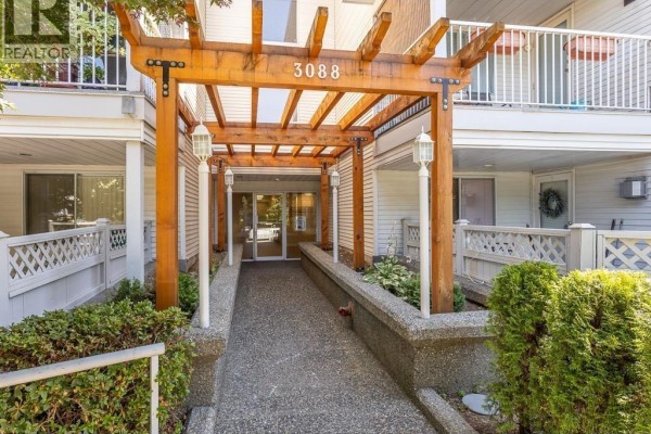 Apartment building lobby with beige tiled floors, gray walls, elevator, and glass doors. - 103 3088 Flint Street, Port Coquitlam