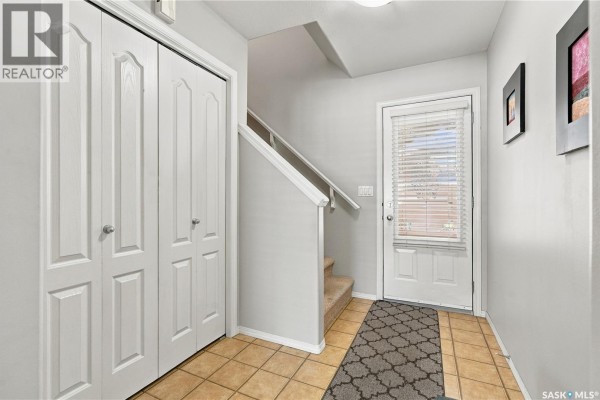 Foyer with beige tile flooring, a white front door, and a bi-fold closet. - 103 445 Bayfield Crescent, Saskatoon