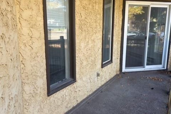 Concrete patio area with two windows and a sliding glass door. - 103 507 Tait Crescent, Saskatoon