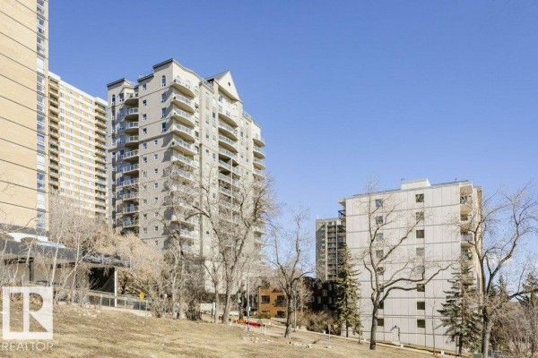View of apartment buildings and trees against a clear blue sky. - #103 9819 104 St Nw, Edmonton