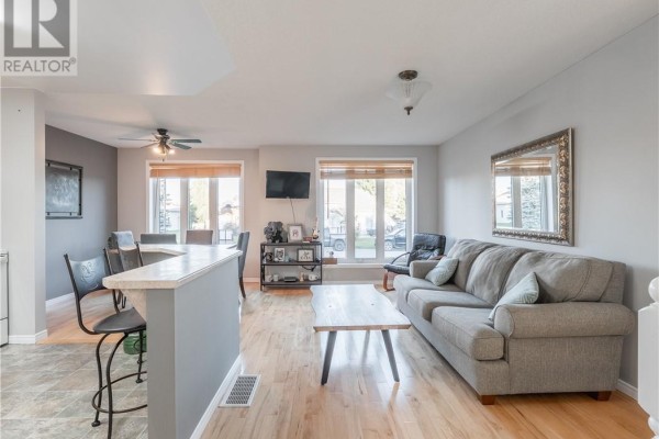 Living room with a grey sofa, coffee table, and large windows overlooking the street. - 103 Cedar Green Drive, Garson