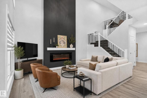 Spacious living room with a tall dark grey fireplace accent wall and a sectional sofa. - 103 Edgefield Wy, St  Albert