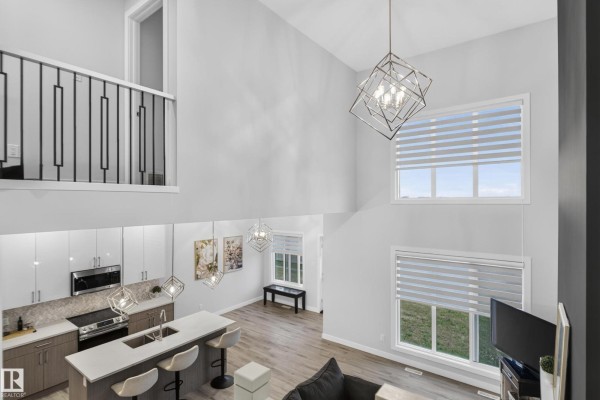 View from the living room couch towards the modern kitchen and staircase. - 103 Edgefield Wy, St  Albert