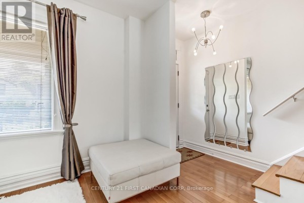 Interior foyer with light wood floors, a white ottoman, a large wavy mirror, and contemporary light fixture. - 103 Edward Street, London South