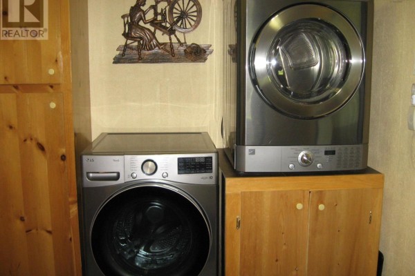 Silver LG washing machine and dryer stacked on top of wooden cabinets. - 103 Highway 8, Milton